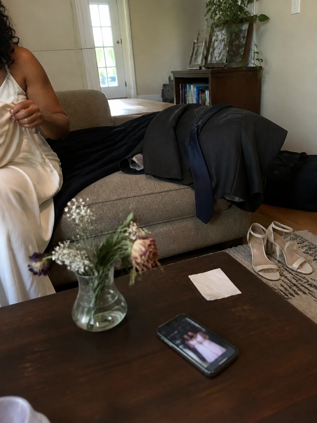 Wedding clothes, shoes, flowers, and a phone left together at home after the celebration.
