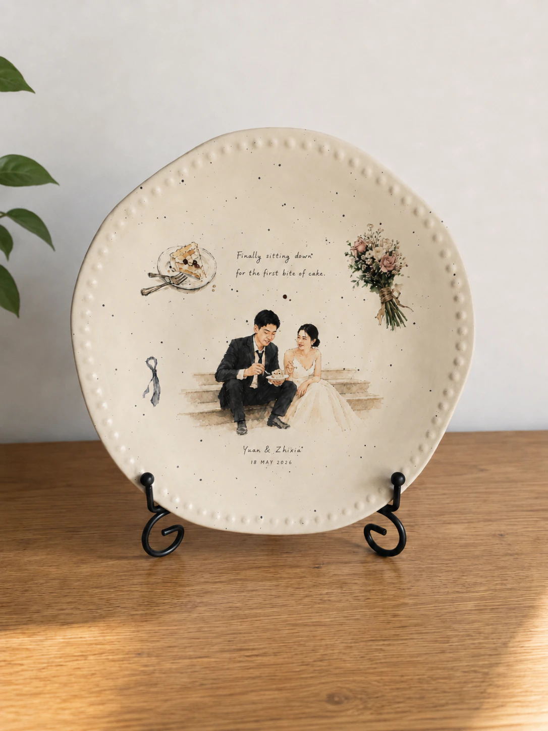 Photographed warm ivory ceramic plate displaying Yuan and Zhixia's wedding story artwork on a tabletop stand.