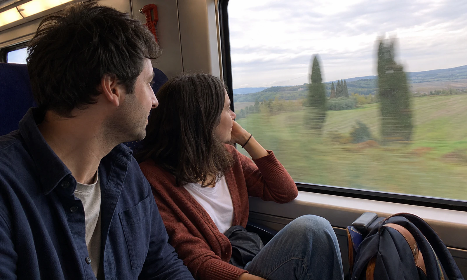 Source photograph of a couple looking out through a train window at the countryside.